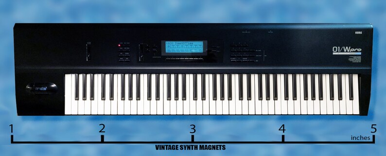 Peut inclure: Un clavier de synth&eacute;tiseur num&eacute;rique noir avec un &eacute;cran LCD bleu et le texte "D1/Ware" en haut &agrave; droite. Le clavier mesure 12,7 cm de large.