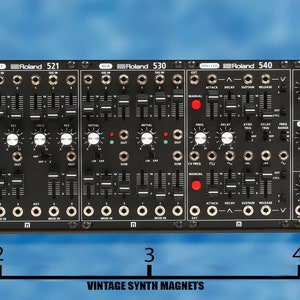 May include: A black Roland System-100M synthesizer module with five individual modules labeled Roland 512, Roland 521, Roland 530, Roland 540, and Roland 572. The module is 19 inches wide and has a wooden side panel.