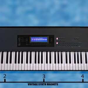 Peut inclure: Un clavier Korg T2 noir avec un clavier de 61 touches, un &eacute;cran LCD bleu et une vari&eacute;t&eacute; de boutons et de molettes. Le clavier mesure 12,7 cm de large.