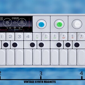 Puede incluir: Un sintetizador blanco con un peque&ntilde;o teclado, botones negros y una pantalla digital. El sintetizador est&aacute; etiquetado como "OP-1" y mide aproximadamente 12,7 cm de largo.