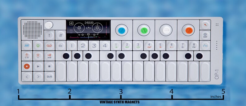 Puede incluir: Un sintetizador blanco con un peque&ntilde;o teclado, botones negros y una pantalla digital. El sintetizador est&aacute; etiquetado como "OP-1" y mide aproximadamente 12,7 cm de largo.