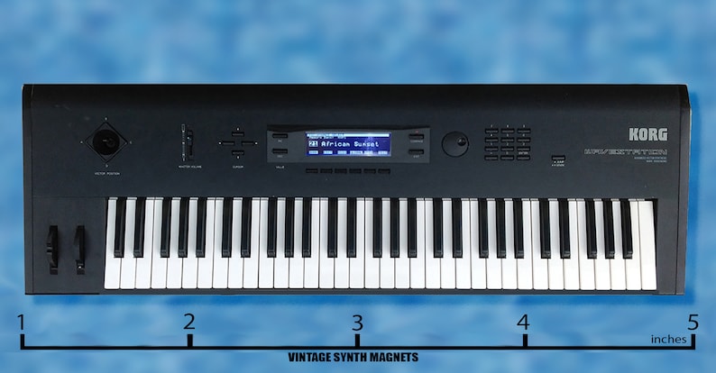 Peut inclure: Un synth&eacute;tiseur Korg MS2000B noir avec un clavier de 61 touches, un &eacute;cran num&eacute;rique affichant "African Sunset" et un panneau de commande avec des boutons et des molettes. Le synth&eacute;tiseur mesure 10 cm de large.
