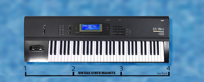 Peut inclure: Un clavier de synth&eacute;tiseur num&eacute;rique noir avec un &eacute;cran LCD bleu affichant "01/W" et le texte "Roland" et "DI/WFD" sur le devant. Le clavier mesure 10 cm de large.