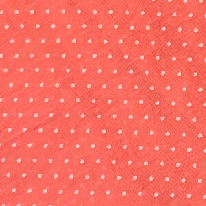 May include: A coral-colored fabric featuring a repeating pattern of small, white, circular polka dots. The material has a visible, slightly textured weave, creating a consistent and uniform appearance across the entire surface of the textile.