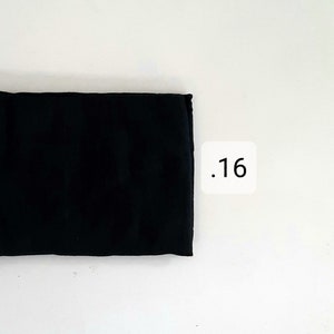 K&ouml;nnte beinhalten: Ein schwarzes Stoffrechteck mit der Nummer .16, die auf einem wei&szlig;en Quadrat gedruckt ist.