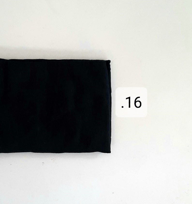 K&ouml;nnte beinhalten: Ein schwarzes Stoffrechteck mit der Nummer .16, die auf einem wei&szlig;en Quadrat gedruckt ist.