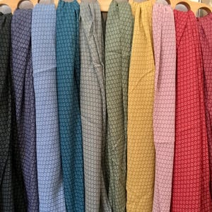 Può includere: Una collezione di dieci campioni di tessuto con un motivo geometrico bianco e grigio. I campioni sono disposti in fila e sono tutti della stessa dimensione. I colori dei campioni sono: nero, grigio scuro, grigio chiaro, verde acqua, verde oliva, giallo, rosa, rosso, bordeaux e marrone.