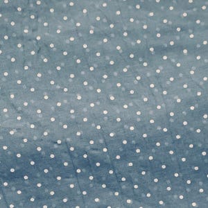 May include: A blue fabric featuring a repeating pattern of small, white, circular polka dots distributed evenly across the surface. The material has a slightly textured appearance with a consistent weave, showcasing a classic and simple design.