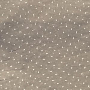 May include: A sheer, light taupe fabric featuring a repeating pattern of small, evenly spaced white polka dots. The material has a delicate, semi-transparent quality with a subtle texture visible across the entire surface of the textile.
