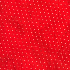 May include: A vibrant red fabric featuring a repeating pattern of small, evenly spaced white polka dots. The material has a slightly textured, semi-sheer appearance with visible weave details throughout the surface of the textile.