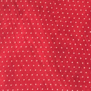 May include: A vibrant red fabric featuring a repeating pattern of small, evenly spaced white polka dots. The material has a slightly textured surface with a consistent weave, creating a uniform and classic dotted design across the entire visible area.
