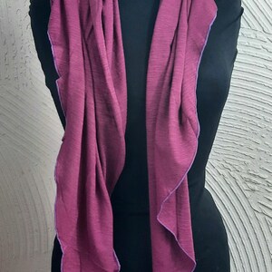 K&ouml;nnte beinhalten: Ein langer, burgunderfarbener Schal mit einem violetten Saum. Der Schal ist &uuml;ber eine schwarze Schaufensterpuppe gelegt.