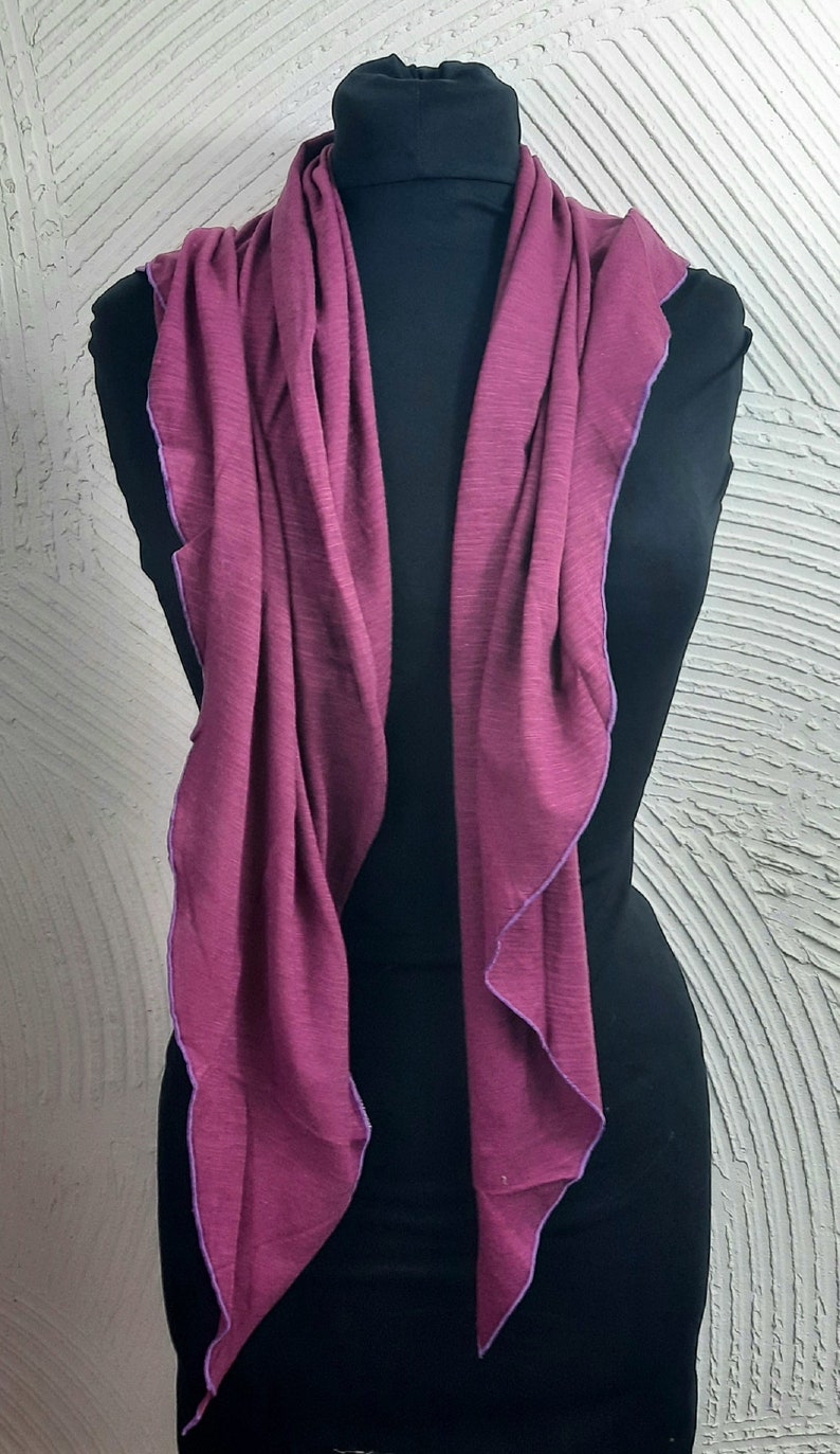 K&ouml;nnte beinhalten: Ein langer, burgunderfarbener Schal mit einem violetten Saum. Der Schal ist &uuml;ber eine schwarze Schaufensterpuppe gelegt.