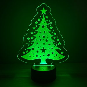 May include: A green LED night light shaped like a Christmas tree with white stars and dots. The light is on a black base with a switch.