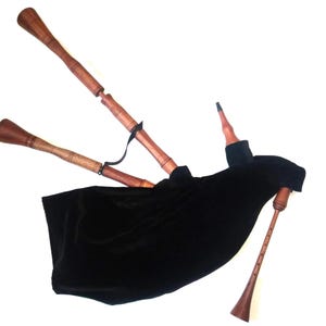 May include: A traditional bagpipe with wooden pipes and a black bag. The instrument features three drones and a chanter, all made of wood. The bag is made of black fabric, and the pipes are connected with black straps.