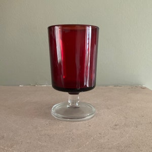 May include: A red glass goblet with a clear glass stem and base.