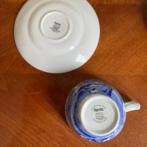 May include: A blue and white Spode teacup and saucer with a floral design. The saucer is plain white with the Spode logo on the bottom. The teacup has a blue and white floral design and the Spode logo on the bottom. The teacup and saucer are dishwasher and microwave safe.