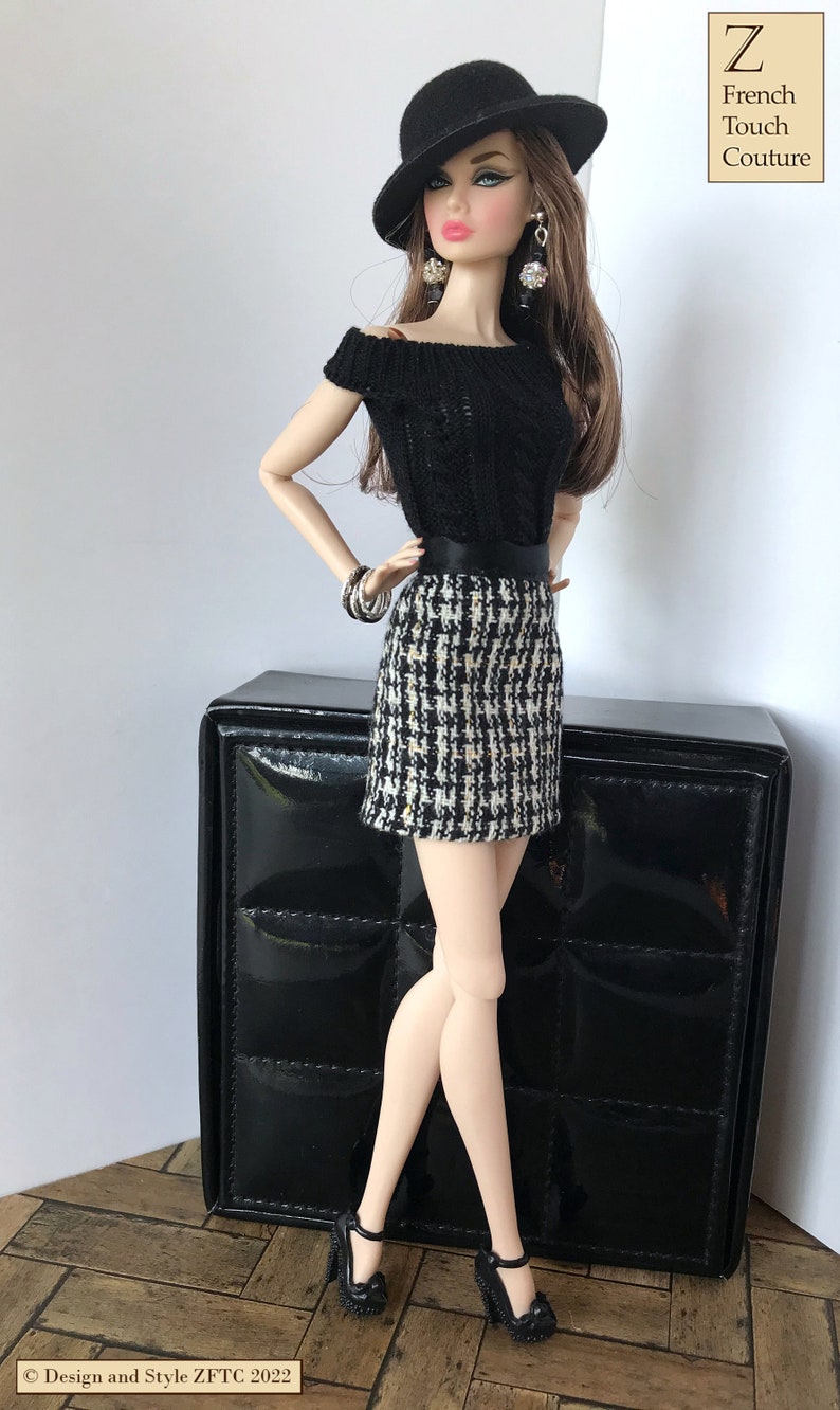 May include: A fashion doll wearing a black and white houndstooth skirt, a black sweater, a black hat, and black shoes. The doll is standing next to a black box with a quilted pattern. The text "Z French Touch Couture" is in the upper right corner of the image.