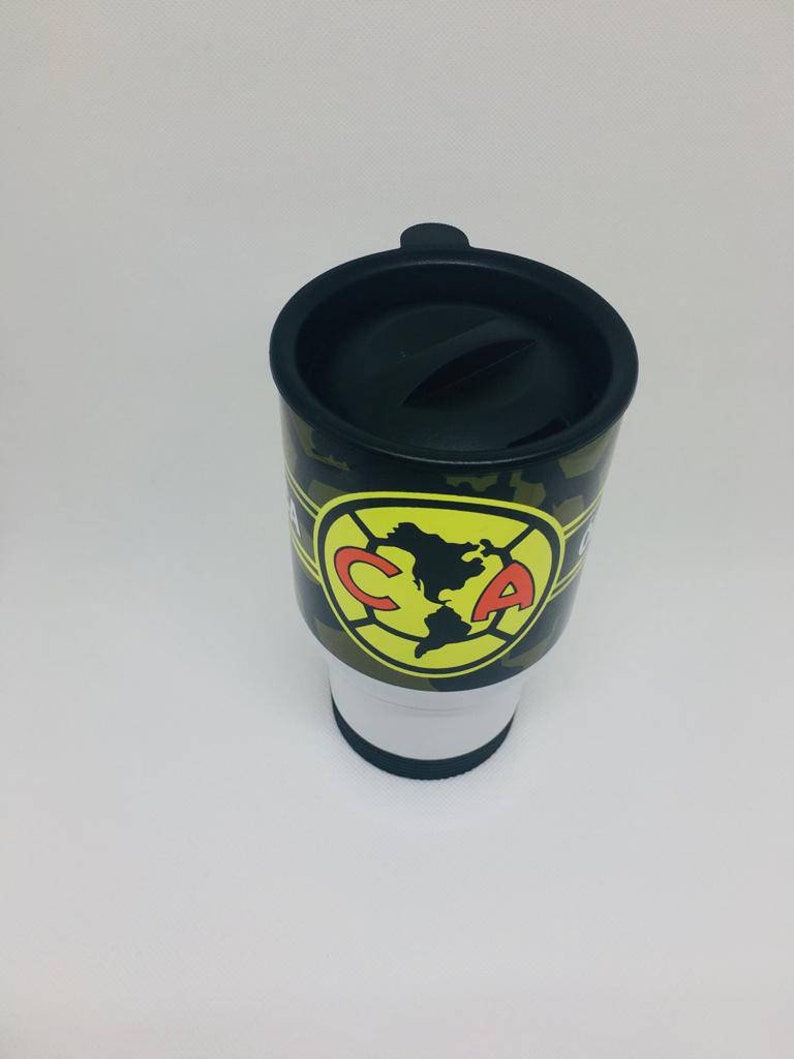 May include: A black and green travel mug with a camouflage pattern and a yellow and red logo that says "CA".