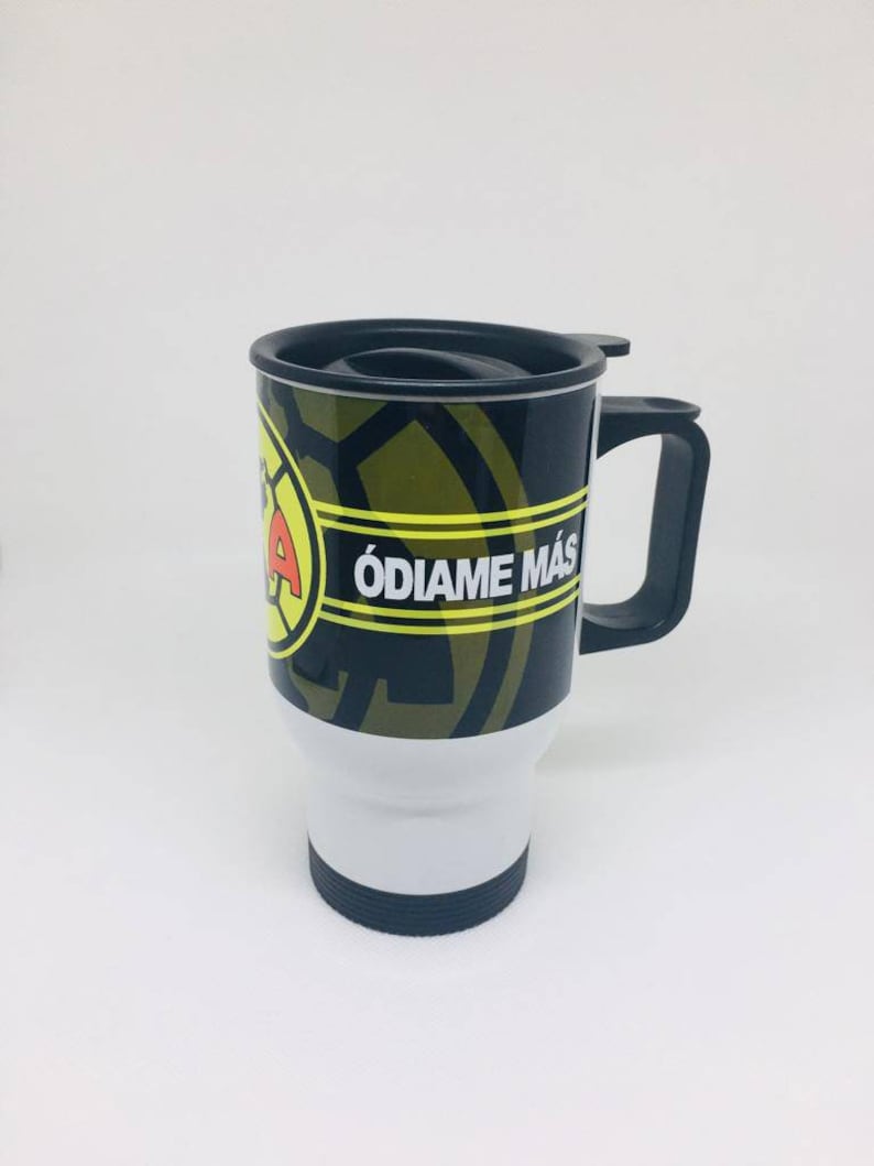 May include: A black and white travel mug with a yellow and black logo and the text "&Oacute;DIAME M&Aacute;S". The mug has a black lid and handle.