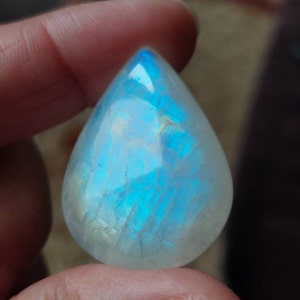 May include: A teardrop-shaped, iridescent moonstone pendant with a blue and white color scheme.