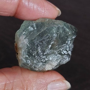 May include: A rough, green and white fluorite crystal with a natural, irregular shape.