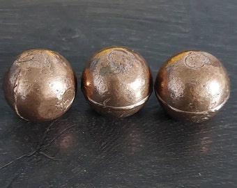 May include: Three round, copper-colored metal balls. The balls have a smooth, slightly textured surface.