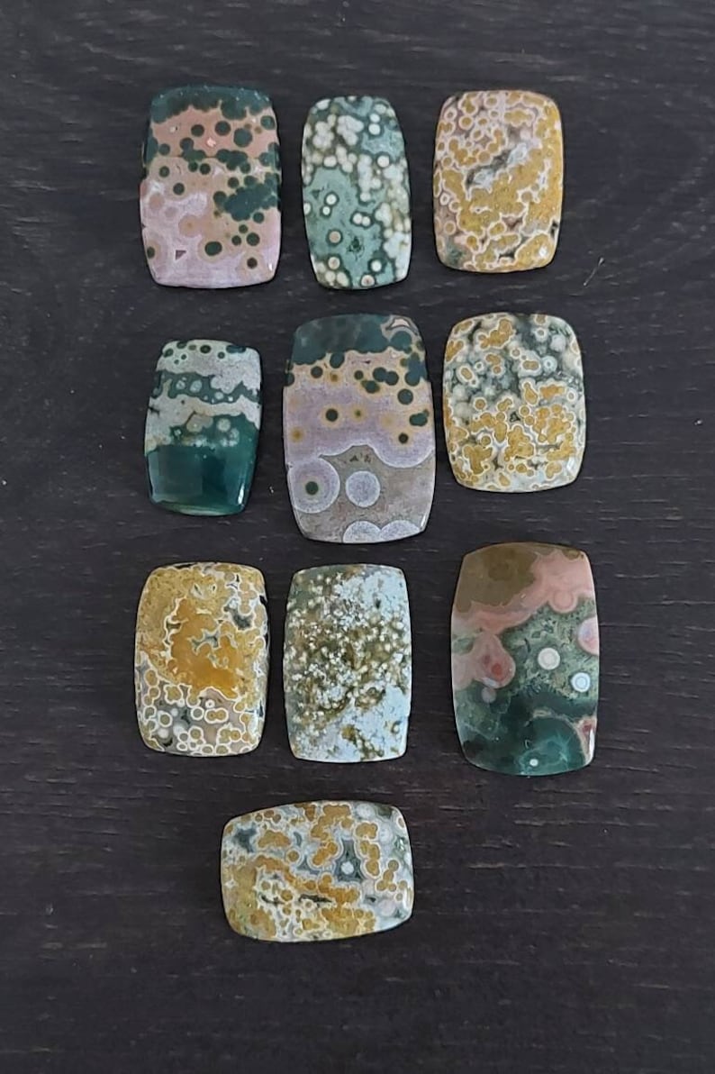 May include: Ten polished, rectangular, ocean jasper stones with a variety of colors and patterns, including green, brown, white, and yellow.