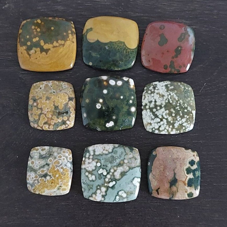 May include: Ten square-shaped polished stones with a variety of colors and patterns, including green, brown, yellow, and white. The stones have a speckled appearance.