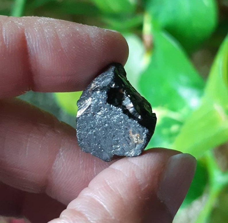 K&ouml;nnte beinhalten: Ein schwarzer, rauer und unregelm&auml;&szlig;ig geformter Stein mit einem leicht metallischen Schimmer.