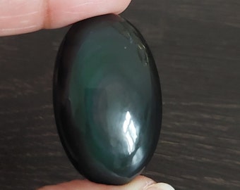 May include: A smooth, oval-shaped black obsidian stone with a green iridescent sheen.