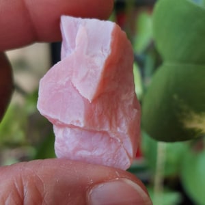 May include: A pink, rough-textured, natural stone with a crystalline structure. The stone is irregularly shaped and has a light pink colour.