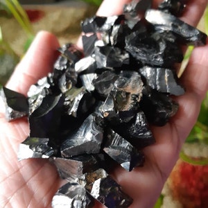 K&ouml;nnte beinhalten: Ein Haufen schwarzer, metallischer, unregelm&auml;&szlig;ig geformter Kristalle. Die Kristalle haben eine gl&auml;nzende, reflektierende Oberfl&auml;che.