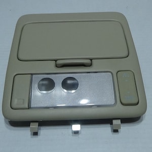 May include: Beige car interior overhead light with two dome lights and two buttons. The buttons are labeled "Map" and "Dome".