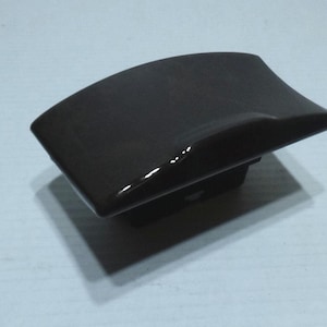 May include: A black plastic car ashtray with a curved top and a rectangular base.
