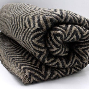 May include: A rolled up black and beige chevron patterned throw blanket.