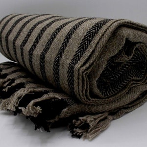 May include: A brown and black striped throw blanket with fringe. The blanket is rolled up and has a textured weave.