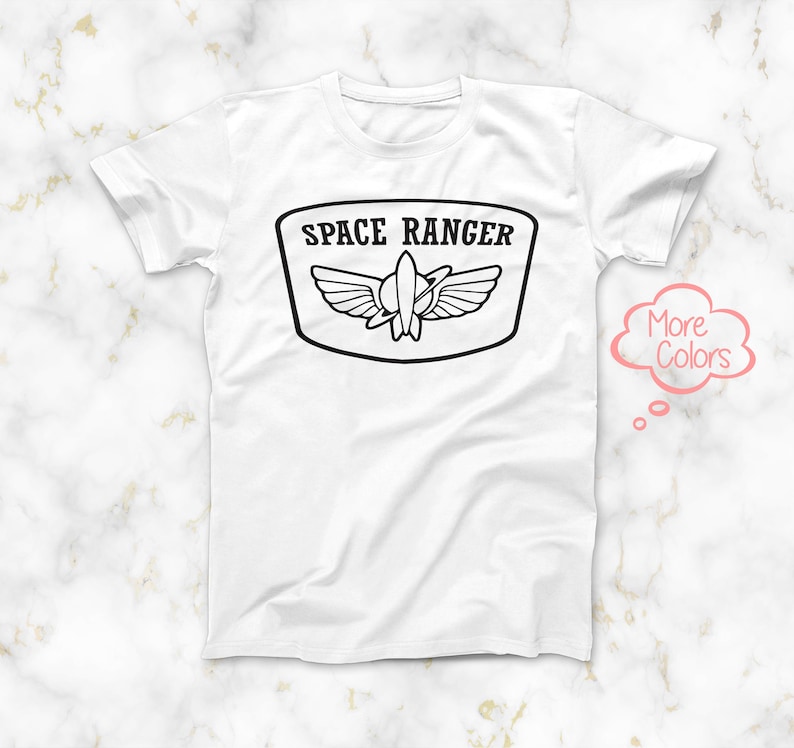 May include: White t-shirt featuring a black graphic of a space ranger patch with the text "SPACE RANGER" and a rocket ship with wings.