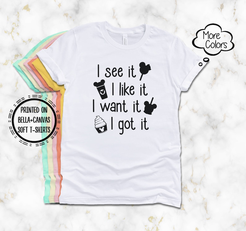 May include: White Bella+Canvas soft t-shirt with the text "I see it, I like it, I want it, I got it" in black. The design includes Mickey Mouse-themed icons. The shirt also has a "More Colors" graphic.