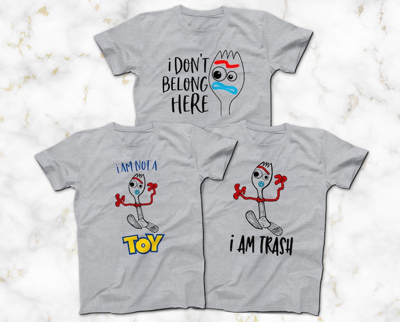 May include: Three gray t-shirts with a cartoon image of a fork with a face and the text "i don't belong here", "i am not a toy", and "i am trash".