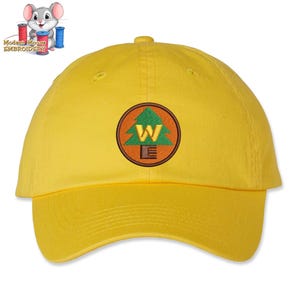 May include: Yellow baseball cap with an embroidered patch featuring a green pine tree and the letters "W.E."