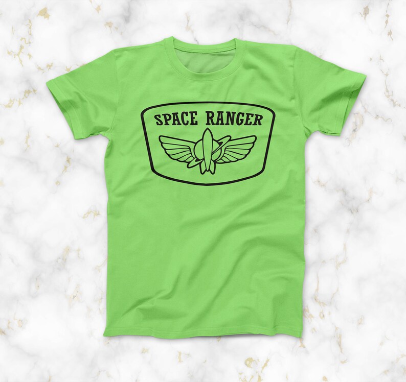 May include: A lime green t-shirt featuring a black graphic of a space ranger badge. The badge depicts a rocket ship with wings and the text "SPACE RANGER".