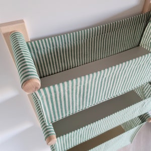 May include: A wall-mounted storage shelf with three green and white striped fabric bins. The shelf is made of wood and has a simple design.