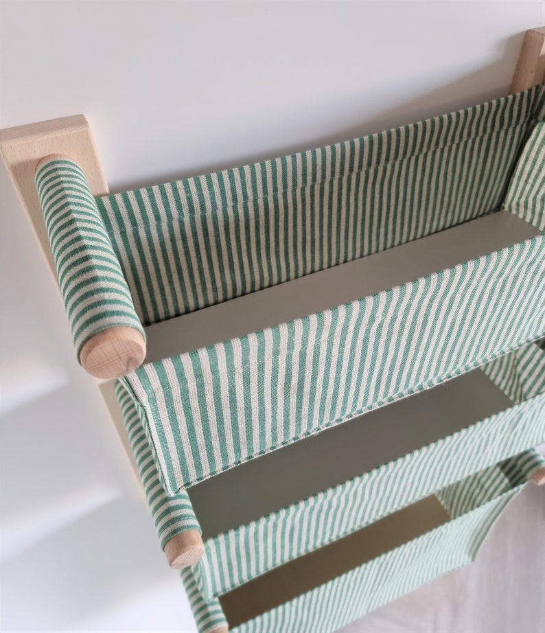 May include: A wall-mounted storage shelf with three green and white striped fabric bins. The shelf is made of wood and has a simple design.