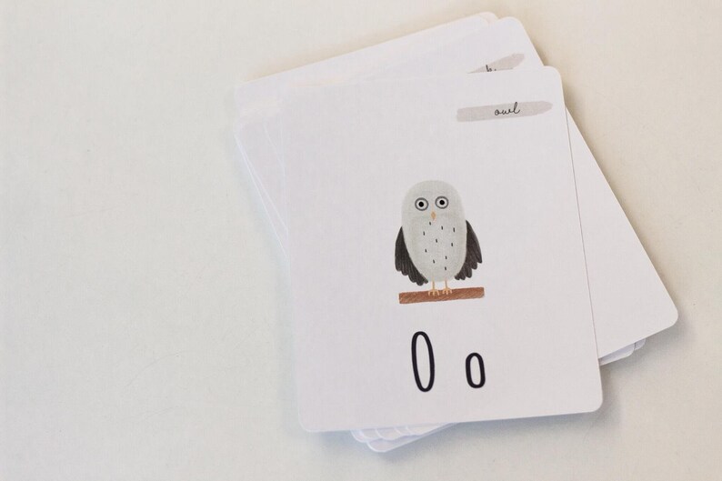 Puede incluir: Una tarjeta blanca con una ilustraci&oacute;n de b&uacute;ho gris y negro y la letra "O" impresa dos veces en negro. La tarjeta tiene la palabra "b&uacute;ho" escrita en cursiva en una etiqueta blanca.