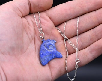 May include: A silver chain necklace with a carved lapis lazuli pendant in the shape of a bird's head.