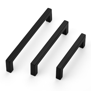 May include: Three black cabinet pulls in varying sizes. Each pull has a rectangular bar and a square, right-angled end. The pulls are arranged diagonally against a white background, showcasing their modern design and finish.