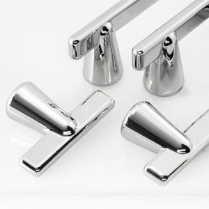 May include: Four T-shaped cabinet pulls with a polished chrome finish. Each pull features a cylindrical base that connects to a horizontal bar, creating a sleek, reflective metallic appearance suitable for furniture or cabinetry hardware.