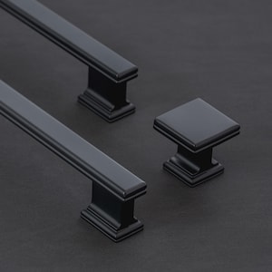May include: Two matte black cabinet pulls with a rectangular profile and a matching square cabinet knob. Each piece features a stepped base design with clean lines and a smooth finish, providing a uniform look for furniture or cabinetry hardware.