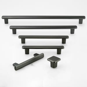 May include: A collection of matte black cabinet hardware including four horizontal bar pulls of varying lengths, one angled bar pull, and one square knob. Each piece features a smooth, elongated design with rounded edges and two mounting posts.